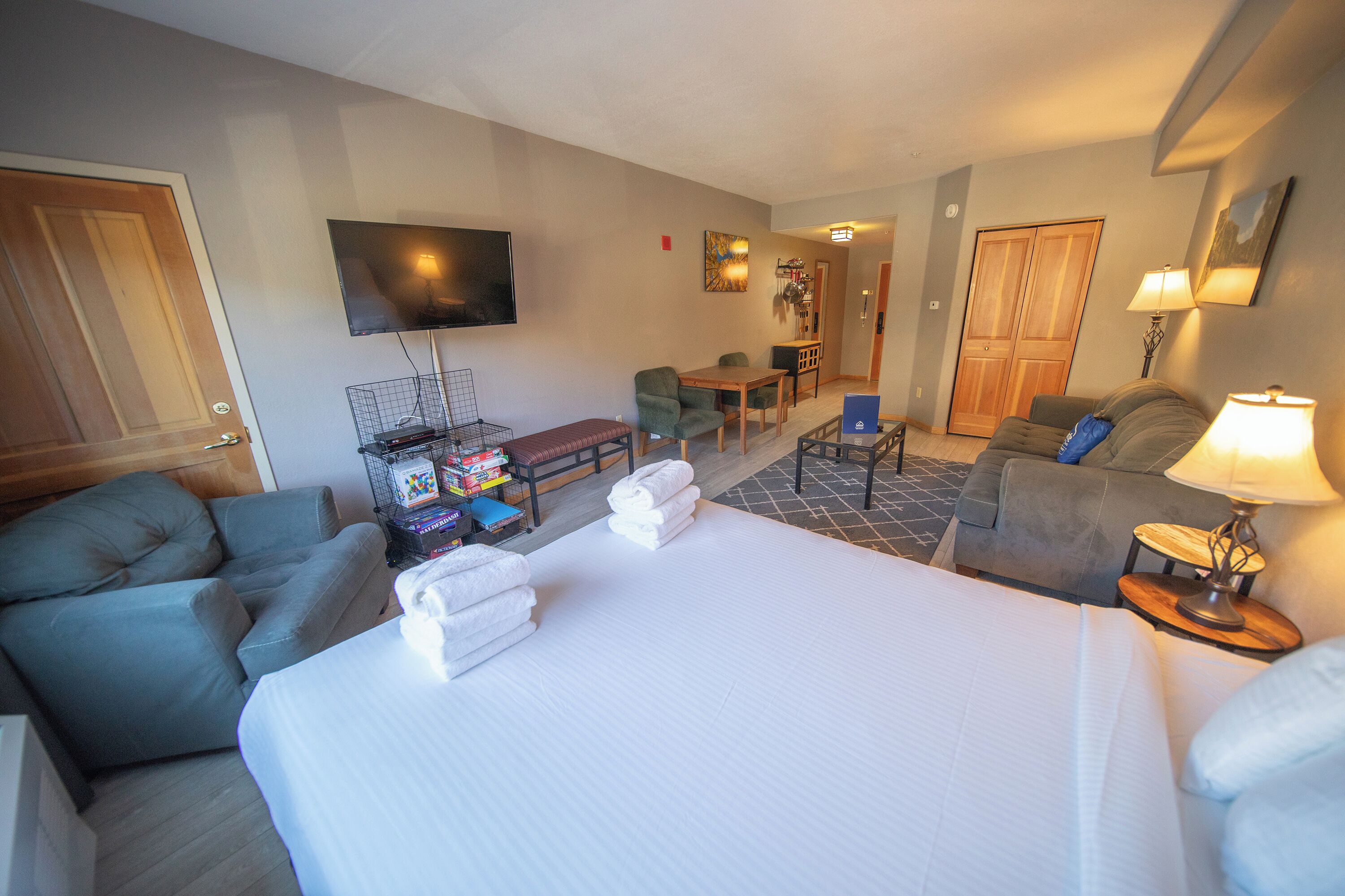 Una camera d'albergo con un letto grande, due divani, una televisione e un piccolo angolo ristoro.