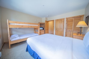 A bedroom with a bunk bed, a single bed, a dresser, and a wardrobe.