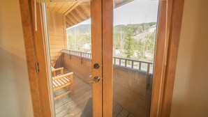 A wooden door leading to a balcony with a view of a mountainous landscape. - Arapahoe Lodge 8119 by SummitCove Lodging (Keystone)