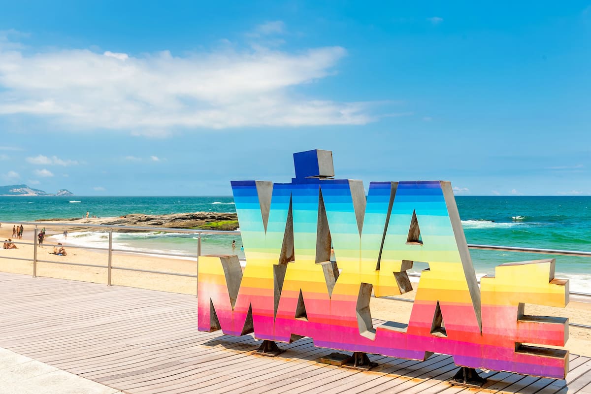 A colorful 'MAYBE' sign on a wooden boardwalk by the beach.