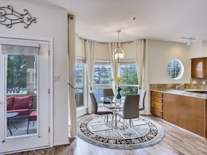 A modern kitchen with a large island, a dining area with a round table and chairs, and a view of the city through large windows.
