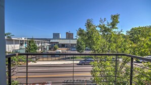 A view of a street with buildings, a parked car, and a metal fence.