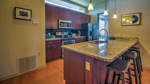 A modern kitchen with dark wood cabinets, stainless steel appliances, and a granite island with bar stools.