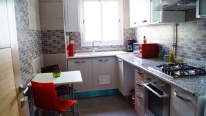 Une cuisine compacte équipée d’un évier, d’une cuisinière et d’un coin repas avec une chaise rouge.