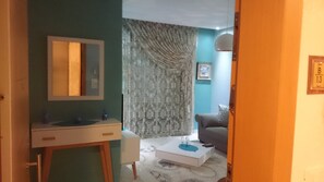 Cozy living space with a minimalist design, featuring a comfortable sofa and a stylish bedside table.