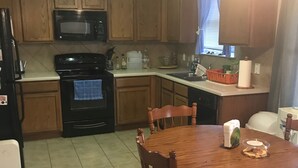 A kitchen with wooden cabinets, a black stove, a microwave, and a dining table with chairs. - Wonderful home (4 bdr, 3 bth) cozy! (Cibolo)