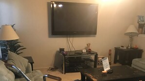 A living room with a sofa, a coffee table, a television mounted on the wall, and a bicycle in the corner. - Wonderful home (4 bdr, 3 bth) cozy! (Cibolo)
