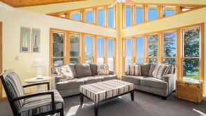 A cozy living room with a high ceiling, large windows, and a comfortable seating area. - Luxury 7BR multifamily on Lake Michigan, Pool & Spa, New Kitchen and Lake Porch! (South Haven)
