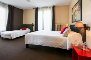 A hotel room with two single beds, a red nightstand, a lamp, and a painting on the wall.
