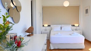 Una habitación de hotel moderna con una cama grande, lámparas de noche, suelo de madera y un espejo decorativo en la pared.