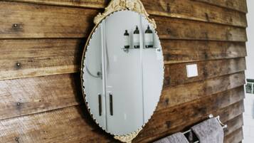 A bathroom with a wooden wall, a white vanity, a mirror, and a towel rack.