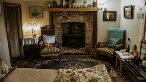 A cozy room with a fireplace, a sofa, a chair, and a table with a lamp. - Belmont Homestead (Swansea)