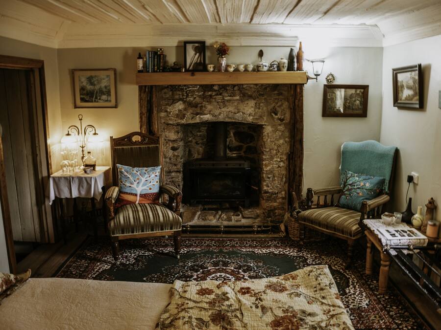 A cozy room with a fireplace, a sofa, a chair, and a table with a lamp.