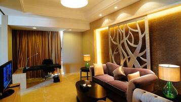 A modern living room with a sofa, coffee table, and a TV. There is a decorative wall panel and a lamp on a side table.