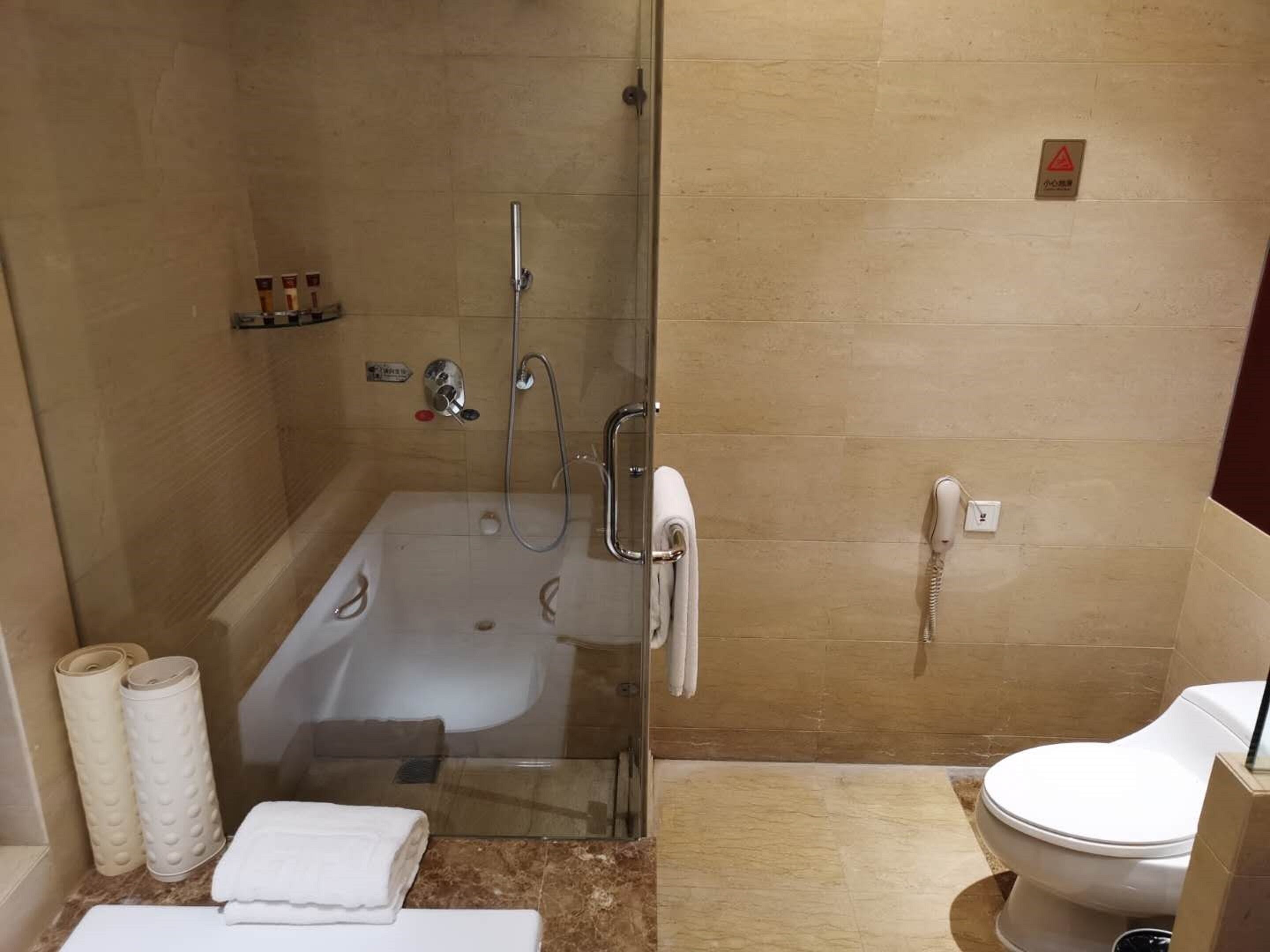 A bathroom with a glass-enclosed shower, a bathtub, a toilet, and a sink.