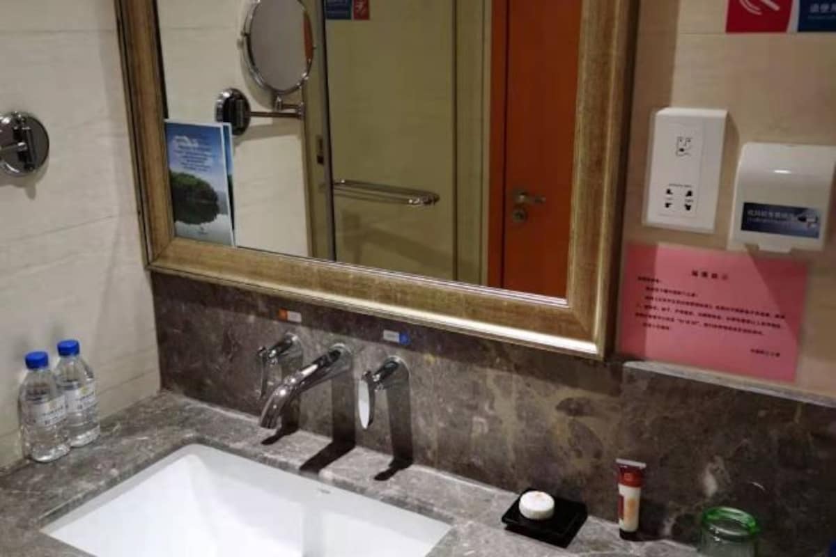 A bathroom with a sink, mirror, and toiletries.