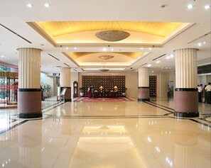 Enter a beautifully designed lobby with polished floors, a striking ceiling, and elegant columns.