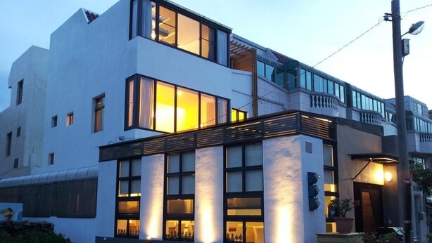 A modern two-story building with large windows and a balcony.