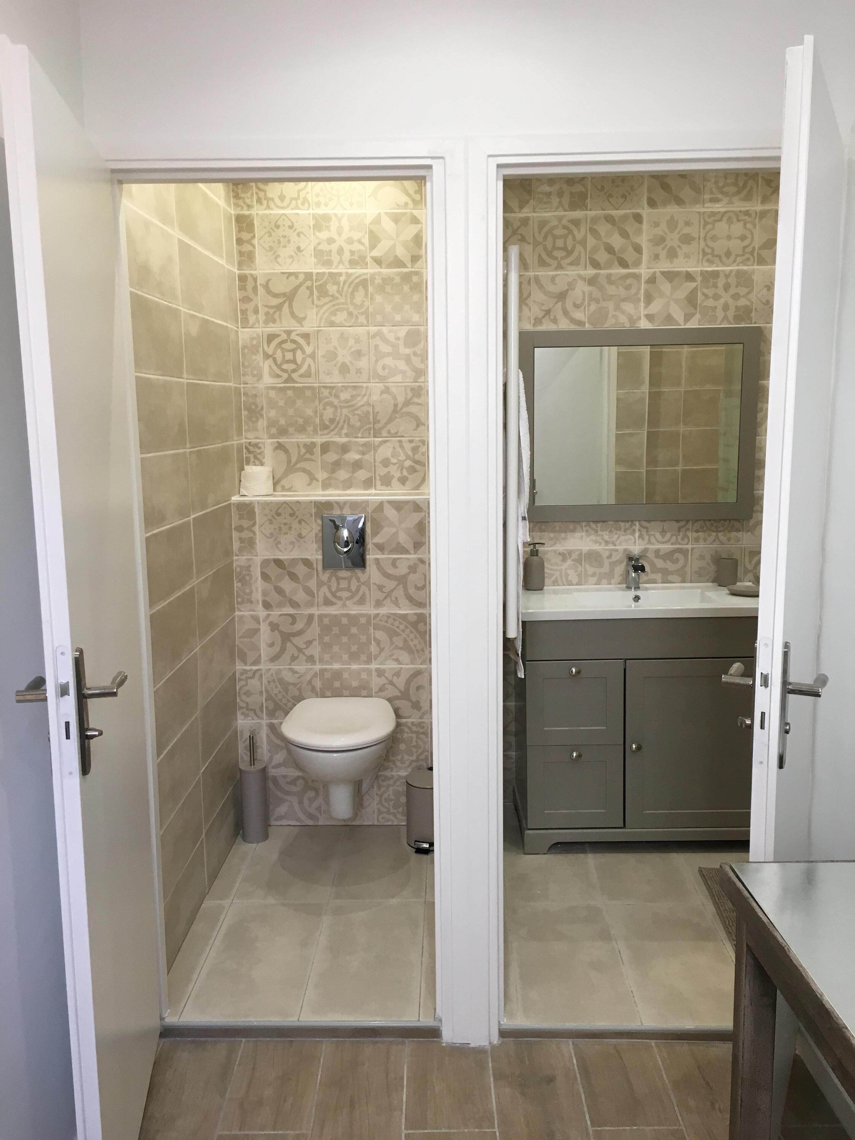 Un baño con inodoro, lavamanos y espejo.