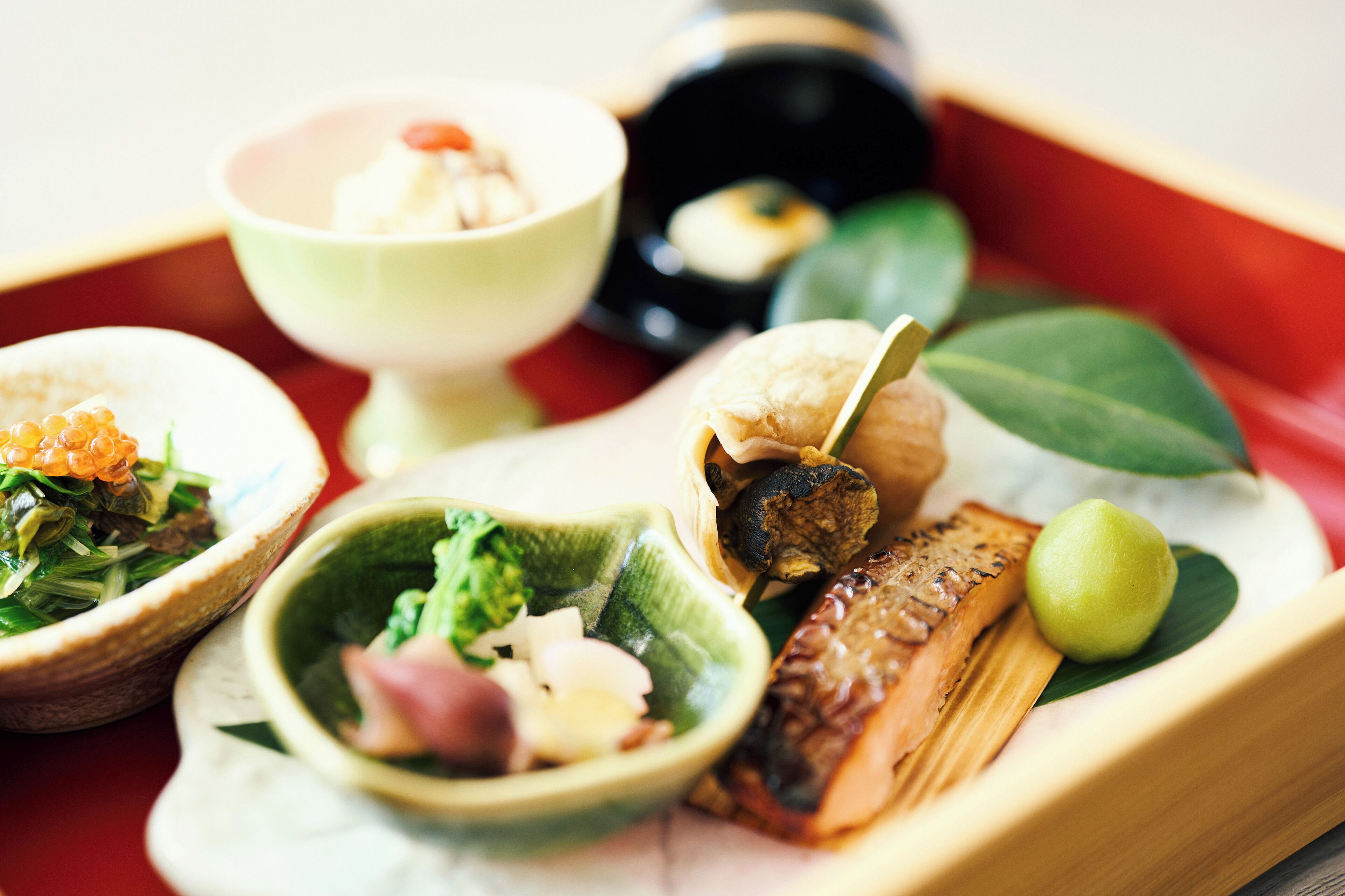 A traditional Japanese meal with various dishes including fish, vegetables, and a small bowl of soup.