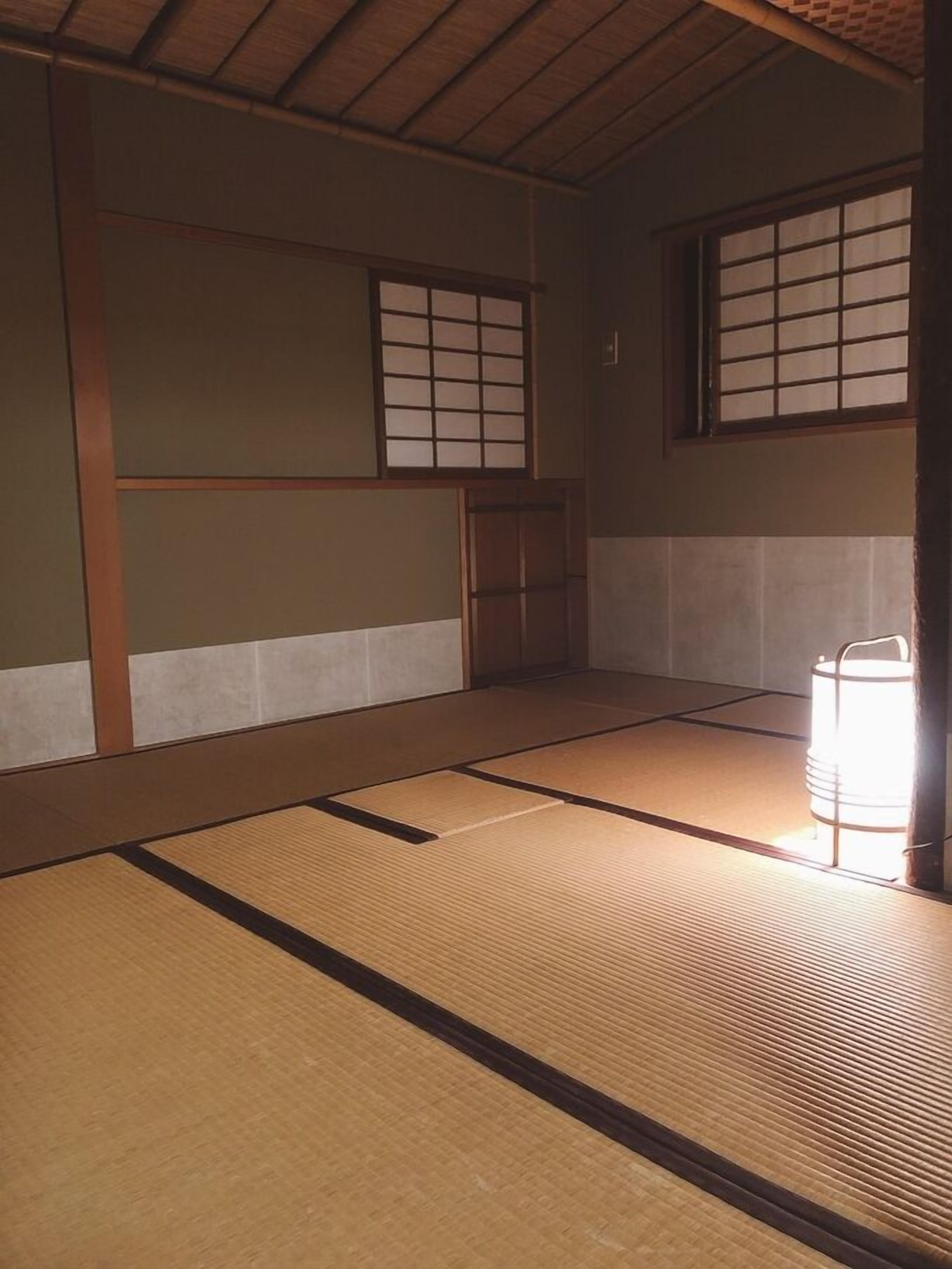 A traditional Japanese room with tatami flooring, shoji screens, and a sliding door.