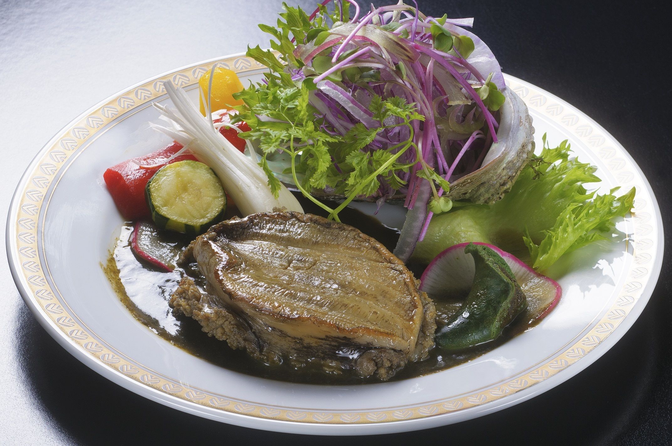 A plate with a piece of meat, vegetables, and a salad.