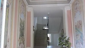 A grand staircase with ornate wall decorations and a potted plant. - Cosy Apartment In The Center Of Krimml, A Stroll Away From Krimml Waterfalls (Krimml)