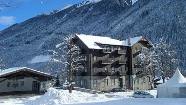 A multi-story building with a sloped roof, surrounded by snow-covered mountains. - Cosy Apartment In The Center Of Krimml, A Stroll Away From Krimml Waterfalls (Krimml)