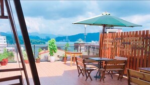 A terrace with wooden furniture and a view of a cityscape and mountains. - Tan Hsiang Yu B&B (Yuchi)