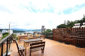 A rooftop terrace with wooden furniture, a view of the city, and directional signs. - Tan Hsiang Yu B&B (Yuchi)