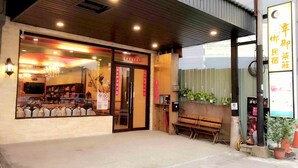 A restaurant with a wooden exterior and a glass entrance. There is a bench outside and a sign with Chinese characters. - Tan Hsiang Yu B&B (Yuchi)