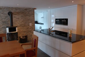 A modern kitchen with white cabinets, a black countertop, and a stone wall.