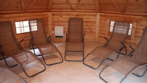 Une pièce comprenant quatre fauteuils inclinables disposés en demi-cercle, des murs en bois et une fenêtre avec des stores.