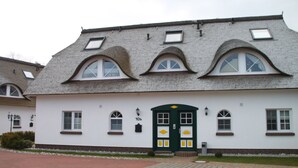 Un bâtiment à la façade blanche, doté d’une porte verte et de nombreuses fenêtres.