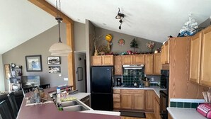 A kitchen with wooden cabinets, a black refrigerator, and a marble countertop. - Red Rock Overlook: A secluded mountain home high above the Uncompahgre River (Ridgway)