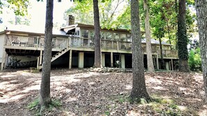 A two-story wooden cabin with a deck, surrounded by trees. - Spacious, Family-Friendly Lake House Retreat w/ a Private Large 2-Story Dock (Cumming)