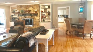 A spacious living room with a fireplace, a dining area with a table and chairs, and a kitchen in the background. - Spacious, Family-Friendly Lake House Retreat w/ a Private Large 2-Story Dock (Cumming)