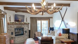 A cozy living room with a fireplace, a wooden table, and a chandelier. - Whistlepunk #4 - Complete Renovation, Truly Slopeside, Near 2 Lifts & Village (Snowshoe)