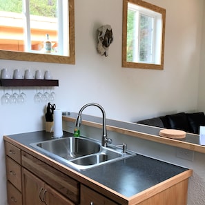 Kitchen features a stainless steel sink, wooden countertop, and wine glasses on the wall.