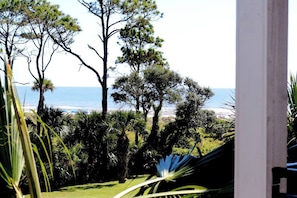 Enjoy the tranquil ocean views from this serene outdoor space surrounded by lush trees and a well-manicured lawn.