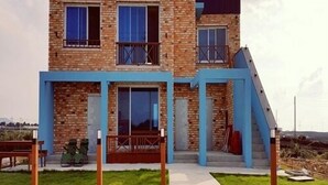 A two-story brick house with a blue exterior and a front porch. - Jeju Sky Sea Pension (Jeju City)