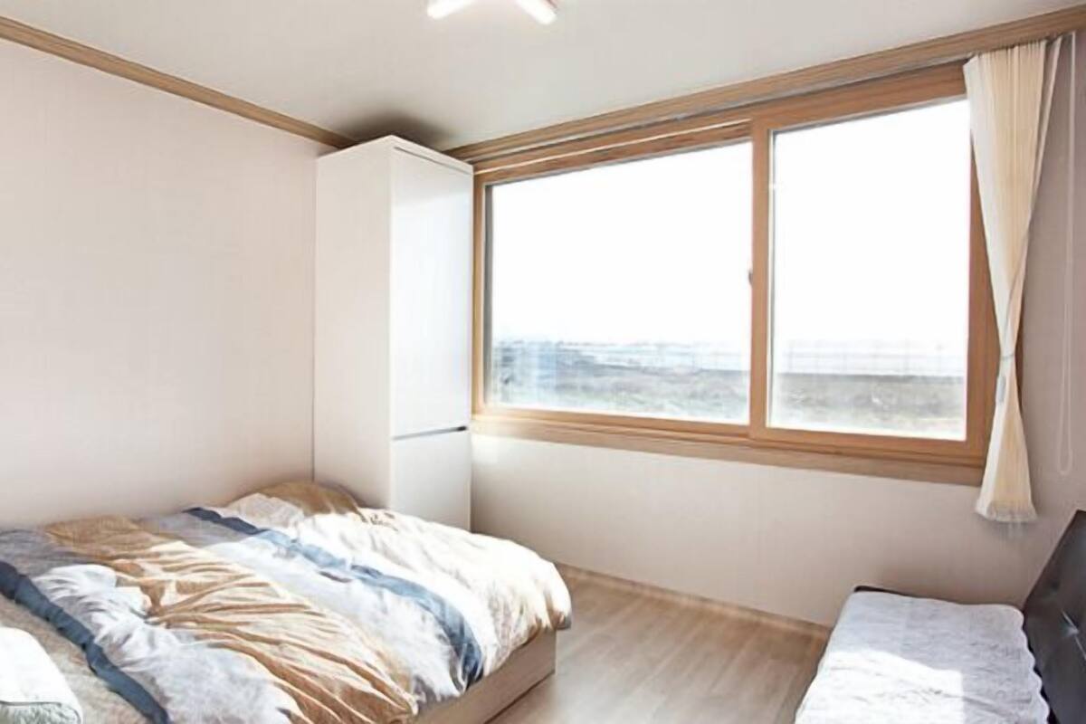 Un dormitorio con cama, ventana con cortinas y armario.