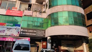 Un edificio de varios pisos con fachada de vidrio curvada, balcones y diversos establecimientos comerciales en la planta baja.
