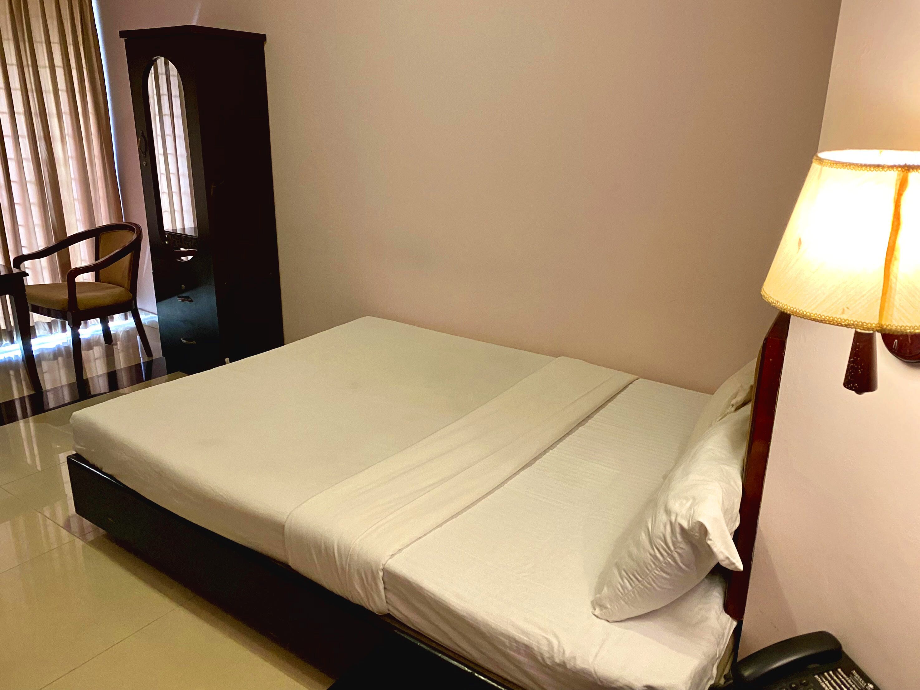 Una cama bien tendida con sábanas blancas en una habitación de hotel.