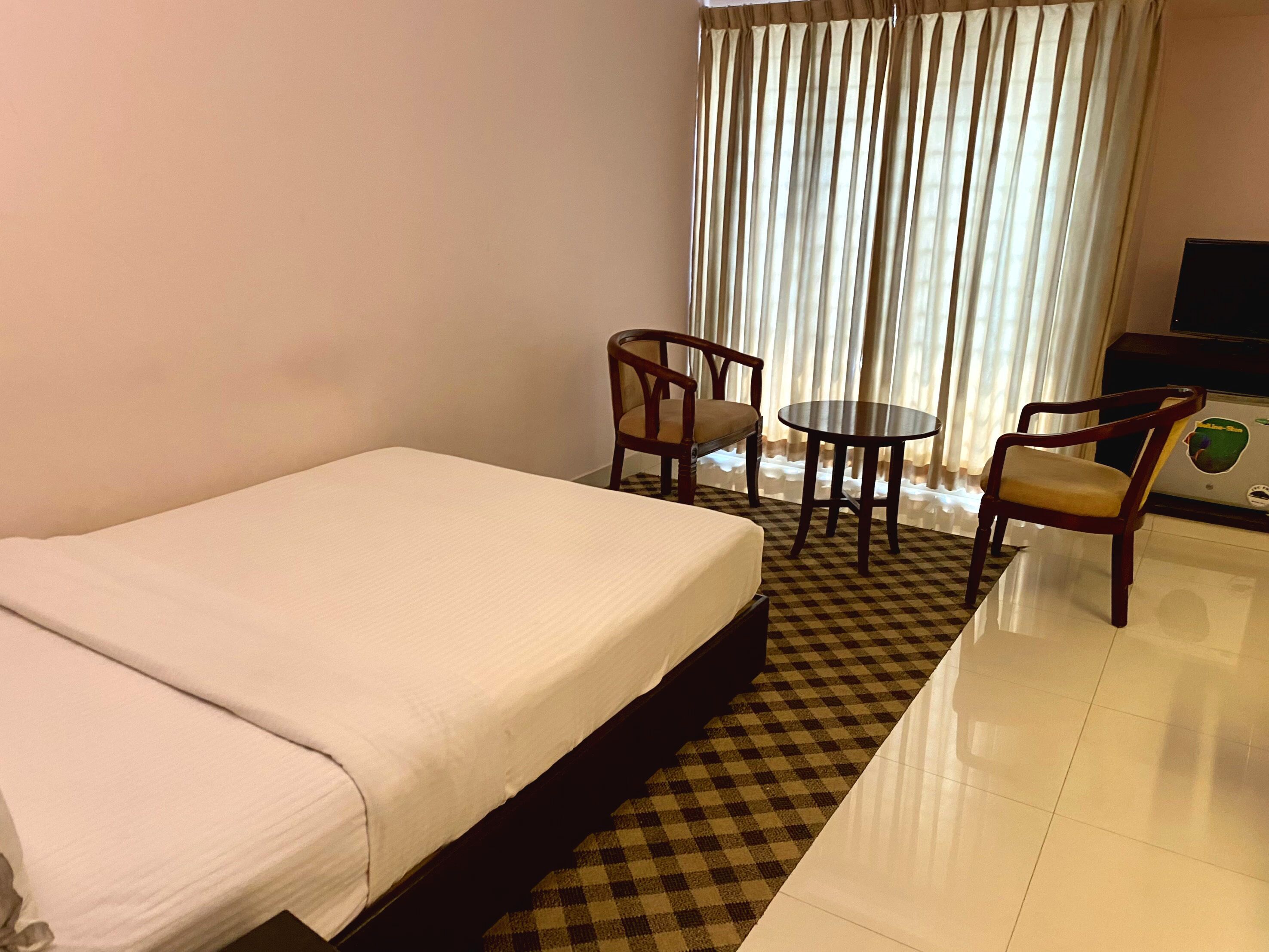 Habitación de hotel con cama, dos sillones, una mesita y televisor.