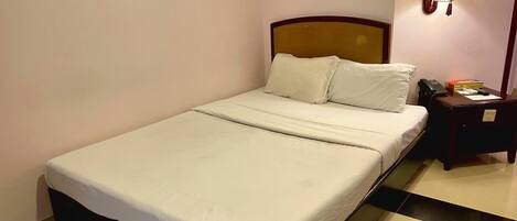 A neatly made bed with white linens in a hotel room.