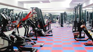 A gym with various exercise machines, a red and blue checkered floor, and mirrors on the walls. - Nirvana Inn (Sylhet)