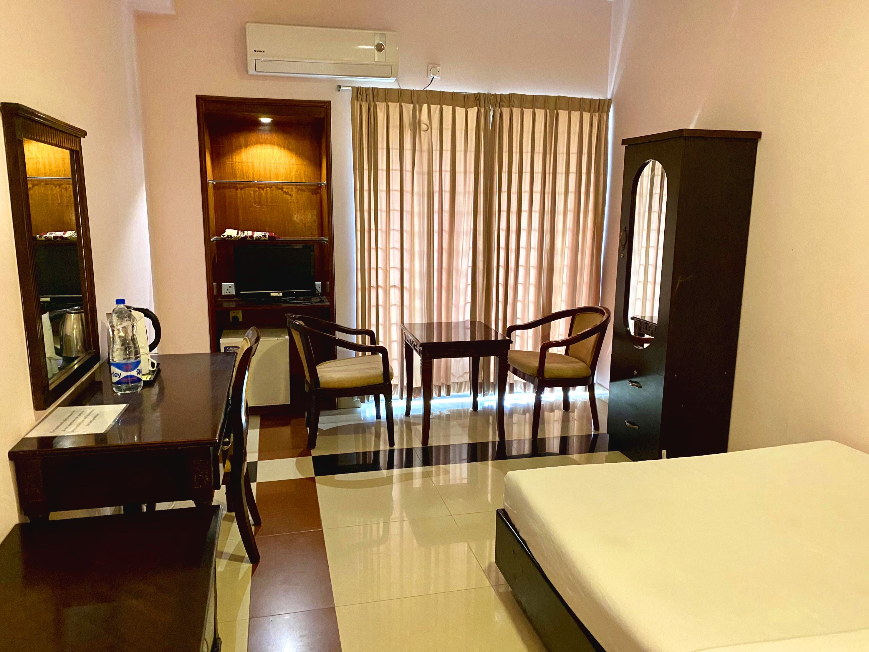 Habitación de hotel con cama, escritorio, silla, televisor y armario.