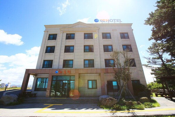 A hotel with a symmetrical facade, multiple windows, and a sign indicating it is a hotel.