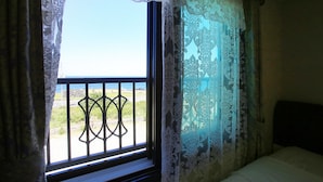 Une pièce avec une fenêtre donnant sur un balcon doté d’une balustrade.